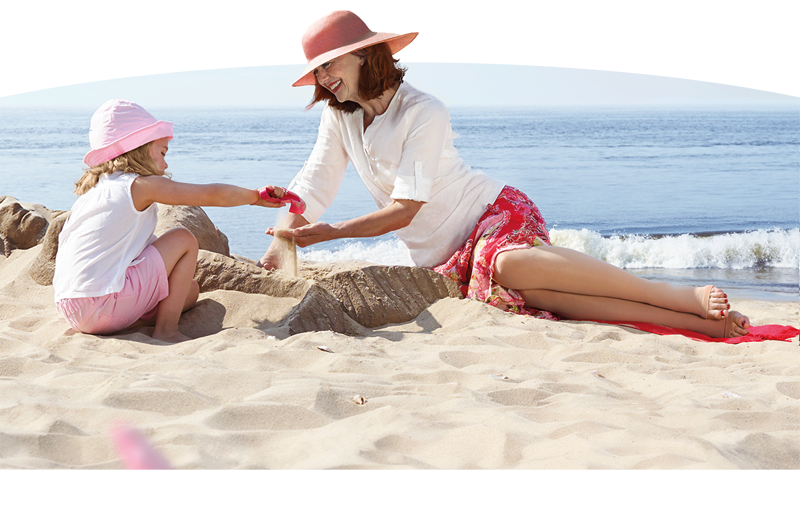 Vrouw en kind spelen samen op het strand met steunkousen aan