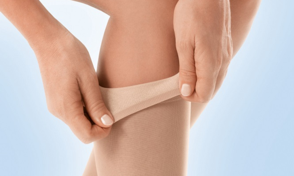 Hand die een steunkous van drukklasse 3 aantrekt op het been